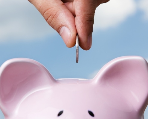 Rosa Sparschwein und Hand, die Geld einwirft
