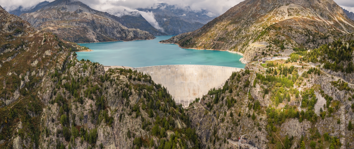 Luftaufnahme mit Panoramablick auf den Emosson-Staudamm und den Emosson-See in den Schweizer Alpen, Stausee für erneuerbare Wasserkraft und Berglandschaft.