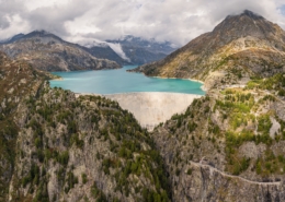Luftaufnahme mit Panoramablick auf den Emosson-Staudamm und den Emosson-See in den Schweizer Alpen, Stausee für erneuerbare Wasserkraft und Berglandschaft.