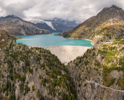 Luftaufnahme mit Panoramablick auf den Emosson-Staudamm und den Emosson-See in den Schweizer Alpen, Stausee für erneuerbare Wasserkraft und Berglandschaft.